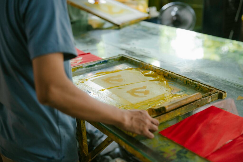 Artisan crafting screen prints indoors, showcasing creativity and skill in handmade art production.